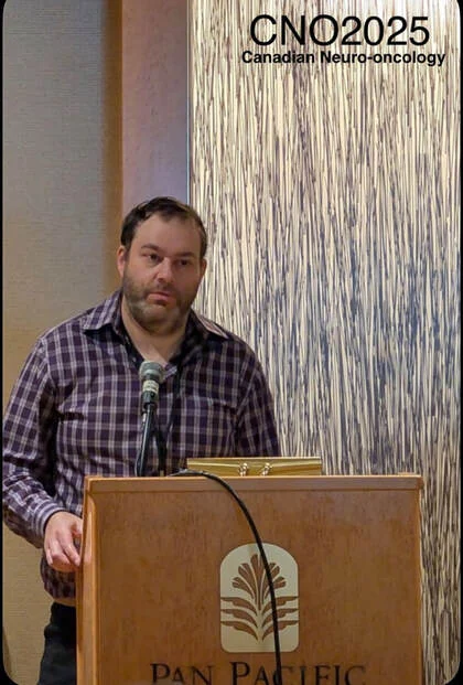Yaron speaking at a podium at the CNO 2025 Canadian neuro-oncology meeting